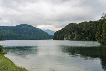 Calm lake surrounded by mountains and lush forests on a cloudy day in Bavaria, Germany