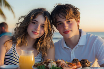 Close-up of young couple at beachside dinner table in casual summer outfits, woman in striped tank top and man in white polo, enjoying seafood and juice at sunset with soft ocean breeze
