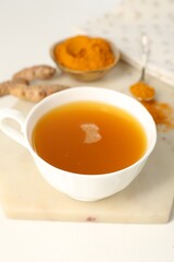 Aromatic turmeric tea, powder and rhizomes on white table, closeup