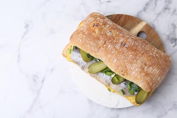 Tasty sandwich with herring, pickles, green onions and parsley on white marble table, top view....