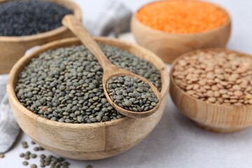 Different types of lentils on light table, closeup