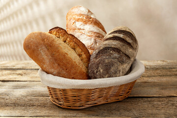 Different loaves of fresh bread in basket on wooden table, closeup