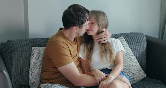 Couple sharing loving embrace on cozy sofa in relaxed setting. Ideal for trust, affection, emotional connection, warmth, domestic life.