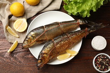Delicious smoked herrings with lemon slices on wooden table, flat lay