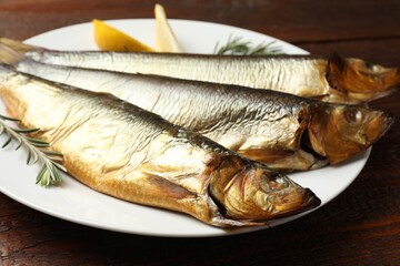 Smoked herrings, rosemary and lemon on wooden table, closeup