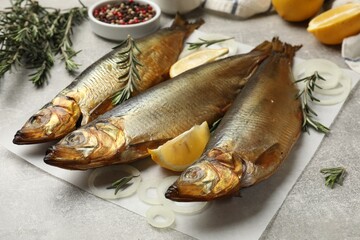 Smoked herrings, onion, rosemary, peppercorns and lemon on light grey table, closeup