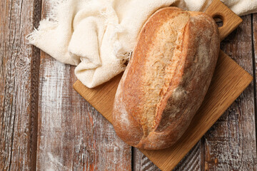 Fresh loaf of bread on wooden table, top view. Space for text