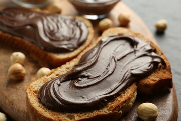 Slices of bread with chocolate spread and hazelnuts on table, closeup