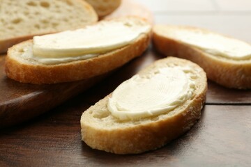 Pieces of bread with butter on wooden table, closeup