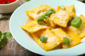 Delicious ravioli with cheese and basil on wooden table, closeup