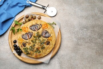 Delicious focaccia with flowers made of vegetables and cutter on grey table, top view. Space for...