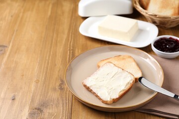 Slices of tasty toasted bread with butter and jam on wooden table, closeup. Space for text
