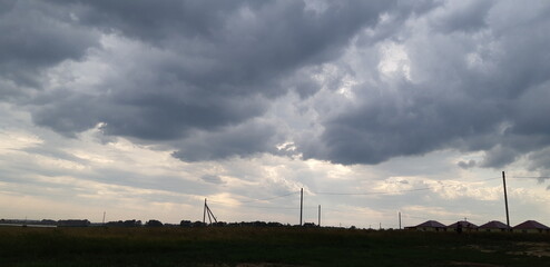Overcast sky with dramatic clouds looming above rural landscape on an early evening