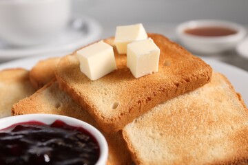 Slices of tasty toasted bread with butter and jam on table, closeup