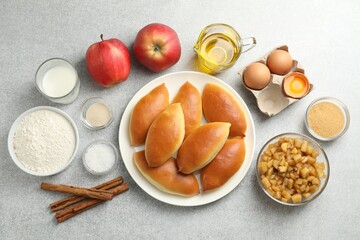 Tasty baked patties and ingredients on light grey table, flat lay