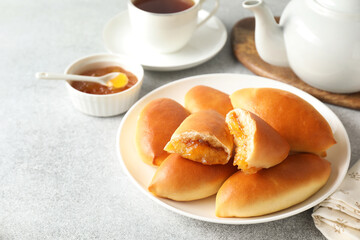 Tasty baked patties with orange jam on light grey table, closeup