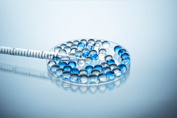 Collagen molecules in Petri dish on blue background. Hyaluronic acid skin care, collagen serum drop. Abstract skin care peptide serum bubble in laboratory.