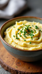 Keto friendly mashed potatoes garnished with chives in a bowl on a wooden table.