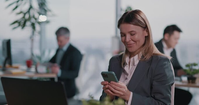 Corporate pretty adult woman using mobile phone notification user interface social network connecting with family working in coworking space.