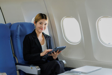 Fototapeta premium While flying to her next destination, an Asian businesswoman concentrates on refining her presentation, preparing to pitch during a crucial business meeting.