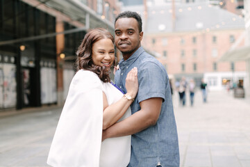 Couple celebrating pregnancy in urban setting with heartwarming embrace during sunny day
