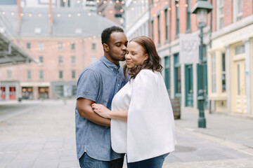Couple enjoys a romantic moment together in a charming urban setting with string lights overhead
