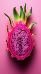Pink dragon fruit crosssection revealing fuchsia flesh against pink backdrop