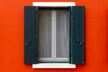 Green shutters on vivid red wall