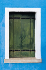Old green shutter on blue wall in Burano