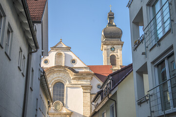 Kirchengebäude und Kirchturm der Konviktskirche im barocken Architekturstil hinter modernen Wohngebäuden in Ehingen an der Donau