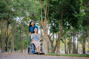 Obraz premium A dedicated physical therapist guides her patient in a wheelchair through the park, sharing a peaceful moment in the fresh outdoor air.