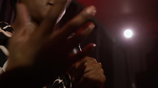 Low angle shot of African American woman holding microphone and giving emotional speech on stage