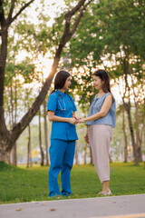 Fototapeta premium In the heart of a lush park, a caring young Asian female doctor guides her elderly patient through gentle exercises, embracing the refreshing, clean air together.