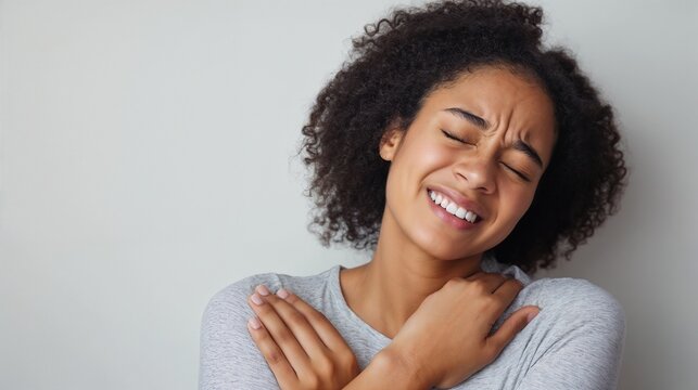 Young woman experiencing joint pain and discomfort after injury on gray background, joint pain awareness concept, modern fitness aesthetic, medical web blogs, medical brochures
