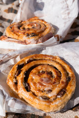 Freshly baked bun on paper wrap during picnic, warm golden crust, casual outdoor food scene in natural light