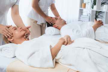 Obraz premium Caucasian couple enjoying relaxing anti-stress head massage and pampering facial beauty skin recreation leisure in dayspa modern light ambient at luxury resort or hotel spa salon. Quiescent