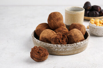 Close up view of Energy balls of chickpeas and dates, sprinkled with cocoa on a plate with a cup of coffee and ingredients at the background, copy space
