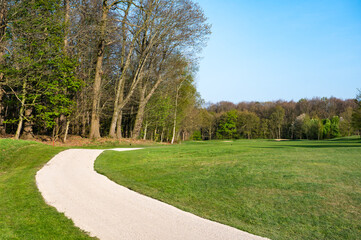 Bending country road through the green meadow at the Flemish countryside in Voormezele, Ieper, West Flanders, Belgium