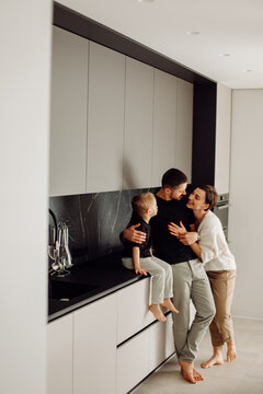 Happy family embracing in modern kitchen: father, mother, and son sharing tender moment