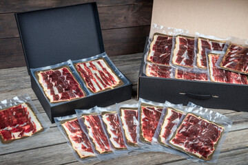 Gourmet gift boxes with vacuum-sealed packs of sliced premium Iberian ham. Copy space.