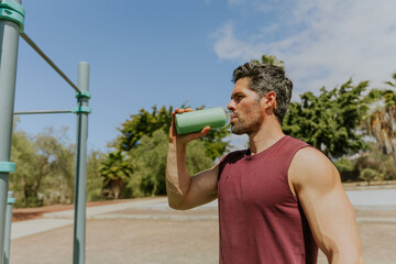 A man is drinking from a bottle during a break while he is working out, hydration in sport in sport