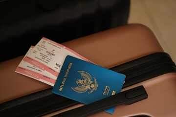 Indonesian passport with tickets lies on touristic suitcase close up in airport waiting hall