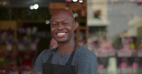 Smiling florist with arms crossed standing in front of colorful flower shop, confident and friendly local business owner posing outside storefront