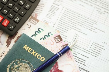 Mexican pesos money bills in big amount lies on table with pen, calculator, passport and tax forms