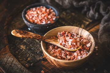 Himalayan salt in a wooden bowl on dark wooden background
