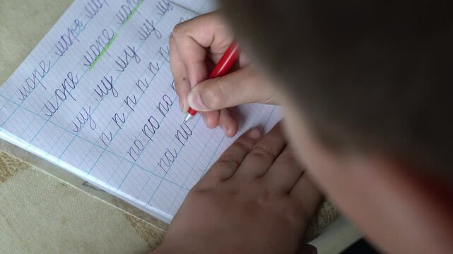 Student practicing cursive handwriting on notebook