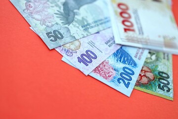 Argentine pesos money bills in big amount lies on red color table close up