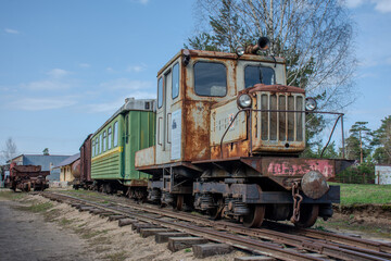 Green train car is parked on the tracks. The train car is old and rusty