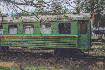 Green train car is parked on the tracks. The train car is old and rusty