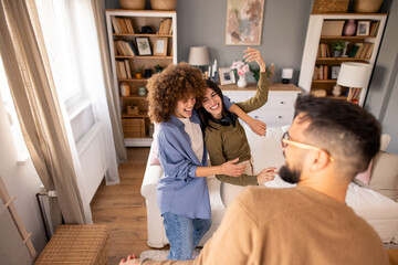 Three Friends Dancing Happily on a Couch in a Bright and Warmly Decorated Room